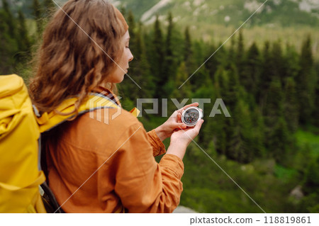 Wanderlust concept. Stylish woman holding a compass in her hand while traveling in the mountains. Wanderlust concept. Stylish woman holding a compass in her hand while traveling in the mountains. 118819861