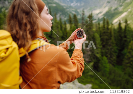 Wanderlust concept. Stylish woman holding a compass in her hand while traveling in the mountains. Wanderlust concept. Stylish woman holding a compass in her hand while traveling in the mountains. 118819862