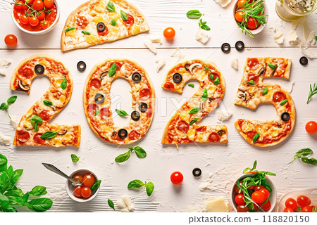 A pizza with the number 25 written in it is on a table with other food items. The pizza is cut into slices and arranged in a way that forms the number 25. The table also has a cup, a bowl, a spoon 118820150