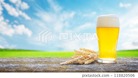 A glass of cold beer placed on a table with a soft outdoor bokeh background A glass of cold beer placed on a table with a soft outdoor bokeh background 118820506