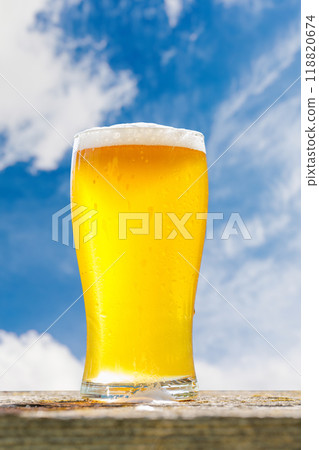A glass of cold beer placed on a table with a soft outdoor bokeh background A glass of cold beer placed on a table with a soft outdoor bokeh background 118820674