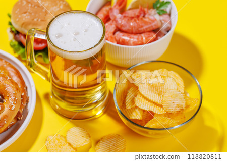A vibrant photo showcasing a glass of beer surrounded by various snacks and fast food A vibrant photo showcasing a glass of beer surrounded by various snacks and fast food 118820811