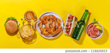 A vibrant photo showcasing a glass of beer surrounded by various snacks and fast food A vibrant photo showcasing a glass of beer surrounded by various snacks and fast food 118820815