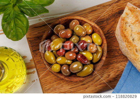 An assortment of various olives presented in a bowl, showcasing different colors, textures, and flavors 118820829