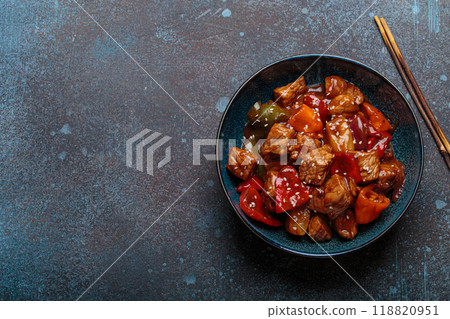 Sweet and sour pork with bell peppers and pineapple served in blue bowl, traditional Chinese dish 118820951