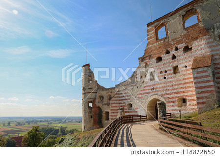 Ruins of a medieval castle with striped walls and wooden walkway in a scenic rural landscape, Poland 118822650