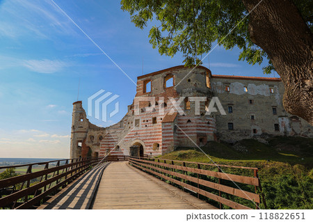 Wooden walkway leading to medieval castle ruins with striped walls, surrounded by scenic landscape, Poland Wooden walkway leading to medieval castle ruins with striped walls, surrounded by scenic landscape, Poland 118822651