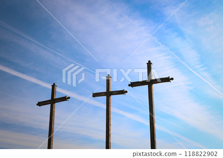 Three wooden crosses under a blue sky with contrails, symbolizing faith, hope, and Christianity 118822902