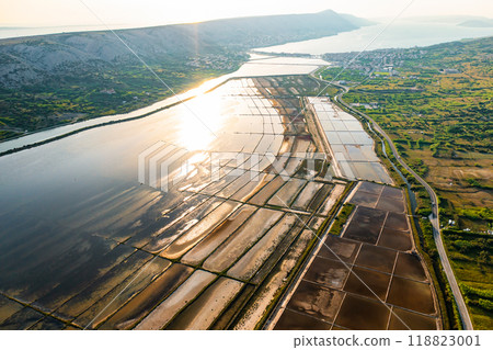 A vast network of salt pans stretches across the landscape, reflecting the sunlight. A vast network of salt pans stretches across the landscape, reflecting the sunlight. 118823001