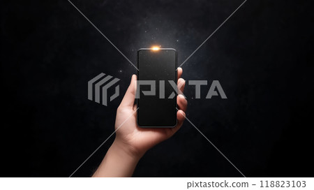 A person holding a smartphone with a glowing light at night 118823103