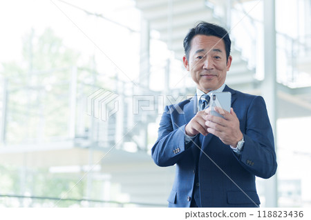 一位中年商人在機場使用智慧型手機 118823436