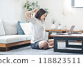 A woman stretching while looking at a laptop in her living room at home 118823511