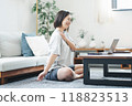 A woman stretching while looking at a laptop in her living room at home 118823513