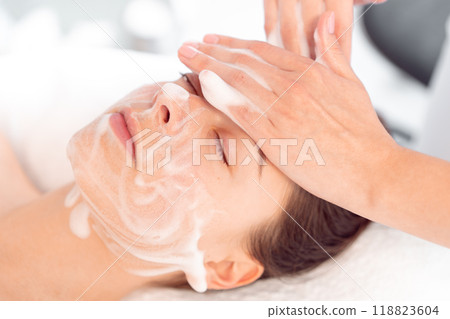 Therapist massaging woman's face with cream at 118823604