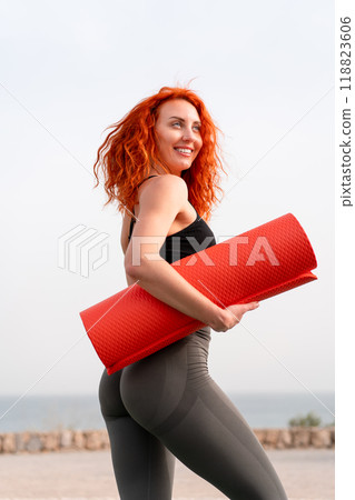 Happy woman with rolled up exercise mat against 118823606