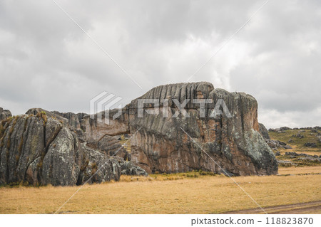 A large rock formation with a small hole in the middle, traveling through the peruvian andes 118823870