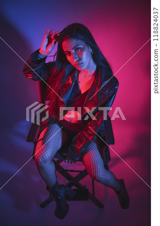 A woman is sitting on a chair in a black jacket and black stockings 118824037