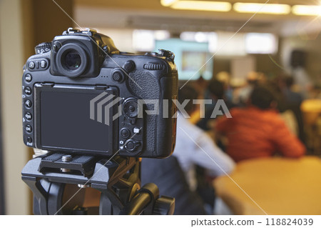 A camera is pointed at a group of people sitting at a table 118824039