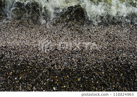 The Pacific Ocean stretches out over a vast sandy beach. The waves carry stones from somewhere. They are washed by the waves and glisten in the sunlight. The Pacific Ocean stretches out over a vast sandy beach. The waves carry stones from somewhere. They are washed by the waves and glisten in the sunlight. 118824963
