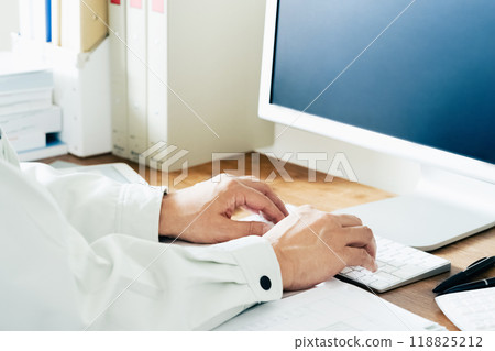 The hands of a man in work clothes operating a computer 118825212