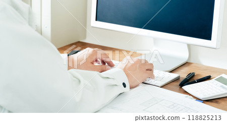 The hands of a man in work clothes operating a computer 118825213