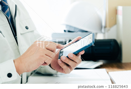 一個穿著工作服的男人操作智慧型手機的手 一個穿著工作服的男人操作智慧型手機的手 118825643