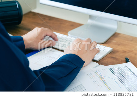 The hands of a man in work clothes operating a computer 118825781
