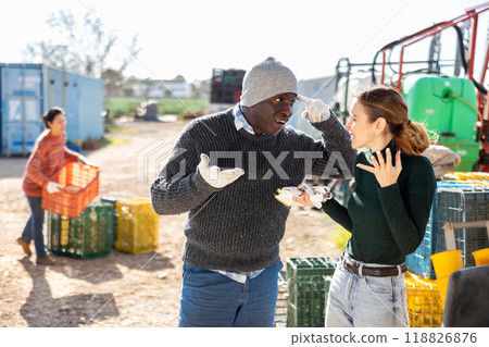 Disgruntled African American farmer reprimanding female worker in farm backyard 118826876