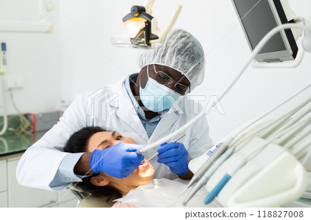 Focused stomatologist treating teeth to female patient in dental office 118827008
