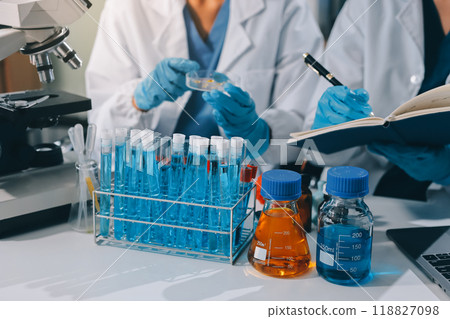 Scientist using microscope in laboratory. Close-up of a researcher's hands adjusting a modern microscope in a lab setting. Science concept 118827098