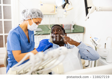 Patient pointing at tooth with problem during consultation in dental clinic 118827219