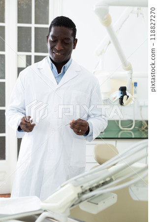 Portrait of a friendly african american dentist doctor in clinic 118827270