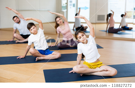 Family doing lotus pose exercises in gym 118827272