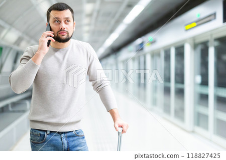 Bearded guy talking on phone on subway station platform Bearded guy talking on phone on subway station platform 118827425