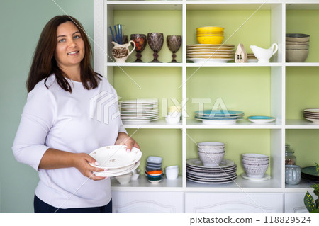 Smiling woman utensil crockery storage organizing method at white vintage shelf closet 118829524