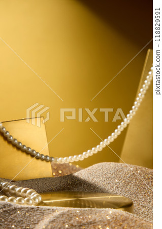 Creative photo of luxury concept from front view on gold background. Empty golden tray in the middle to display the product, a pearl string across in space Creative photo of luxury concept from front view on gold background. Empty golden tray in the middle to display the product, a pearl string across in space 118829591