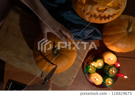 Engaging in the delightful activity of carving pumpkins for a Halloween celebration with candles Engaging in the delightful activity of carving pumpkins for a Halloween celebration with candles 118829673