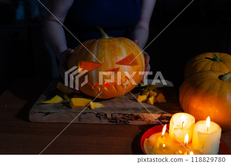 A person is skillfully carving a pumpkin for Halloween on a cutting board A person is skillfully carving a pumpkin for Halloween on a cutting board 118829780