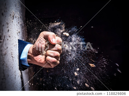 Businessman's fist breaking through a wall Businessman's fist breaking through a wall 118829806