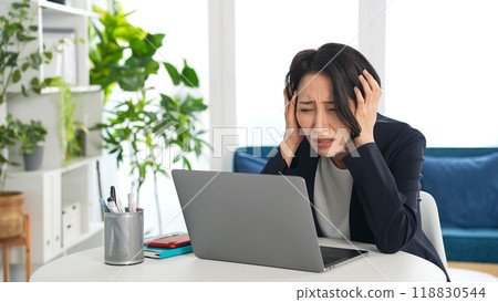 一位憂心忡忡的女商人在辦公室裡看著筆記型電腦 一位憂心忡忡的女商人在辦公室裡看著筆記型電腦 118830544