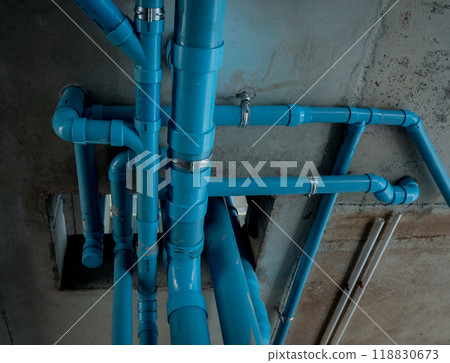 A bright blue pipes attached to a solid concrete wall 118830673
