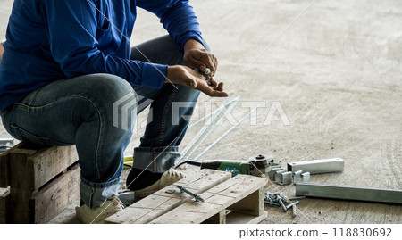 A builder works with screws and nuts on a wooden pallet A builder works with screws and nuts on a wooden pallet 118830692