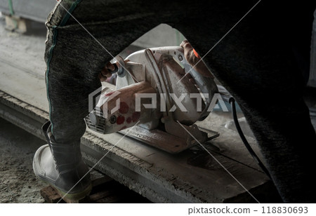 A builder using a circular saw to cut a large concrete piece 118830693