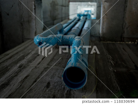 A bright blue pipes attached to a solid concrete wall 118830694
