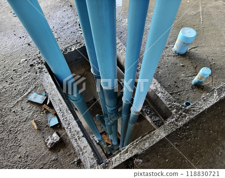 A bright blue pipes attached to a solid concrete wall 118830721