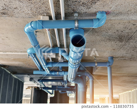 A bright blue pipes attached to a solid concrete wall 118830735
