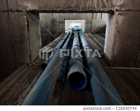 A bright blue pipes attached to a solid concrete wall 118830744