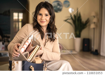A young beautiful woman is collecting her women's bag. He puts away his diary, glasses, keys, phone A young beautiful woman is collecting her women's bag. He puts away his diary, glasses, keys, phone 118831053