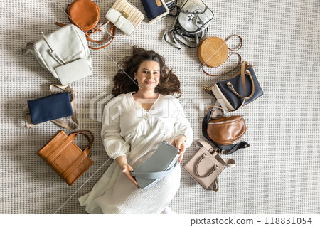 A young beautiful girl lies in the dressing room, surrounded in a circle by many fashionable 118831054