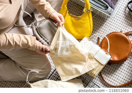A young woman puts fashionable, beautiful bags into fabric bags for neat storage. Home wardrobe. A young woman puts fashionable, beautiful bags into fabric bags for neat storage. Home wardrobe. 118831060